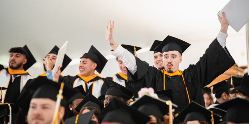 Graduates celebrate under the tent and in regalia at the University of Mount Saint Vincent's Commencement Ceremony