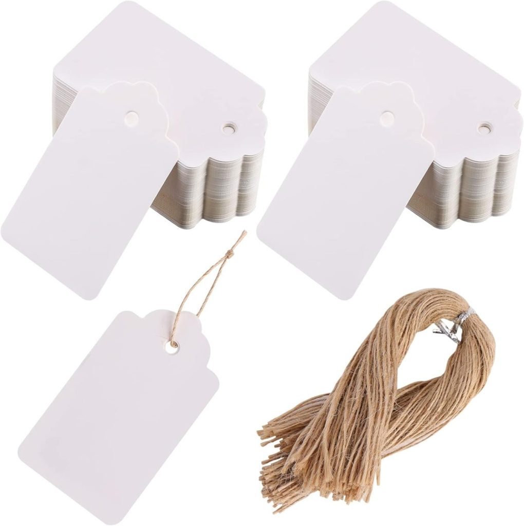 Stacked blank gift tags with a scalloped edge and punched holes, perfect for adding a personalized touch to your gift wrapping, accompanied by a bundle of jute twine.