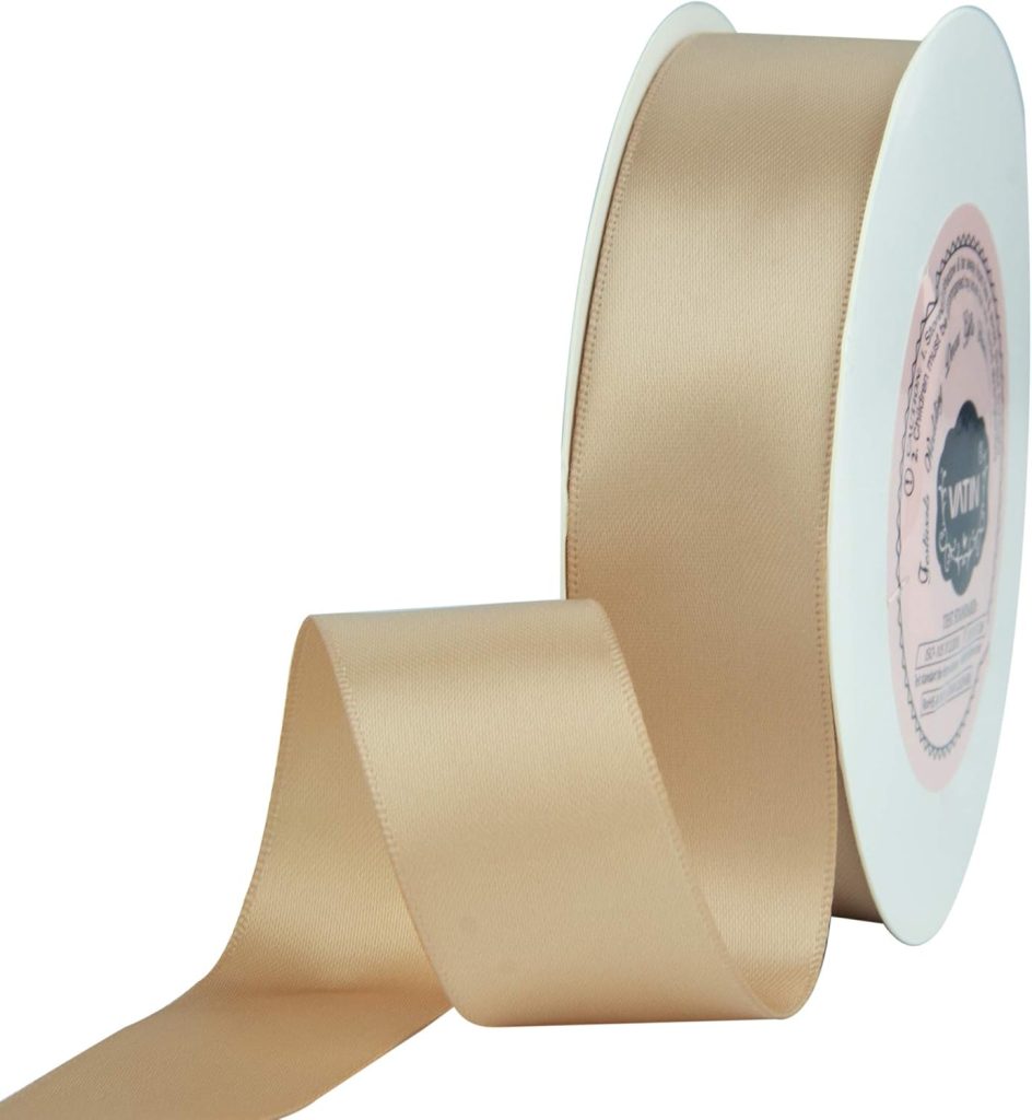 A spool of beige satin ribbon, perfect for gift wrapping, is partially unrolled.