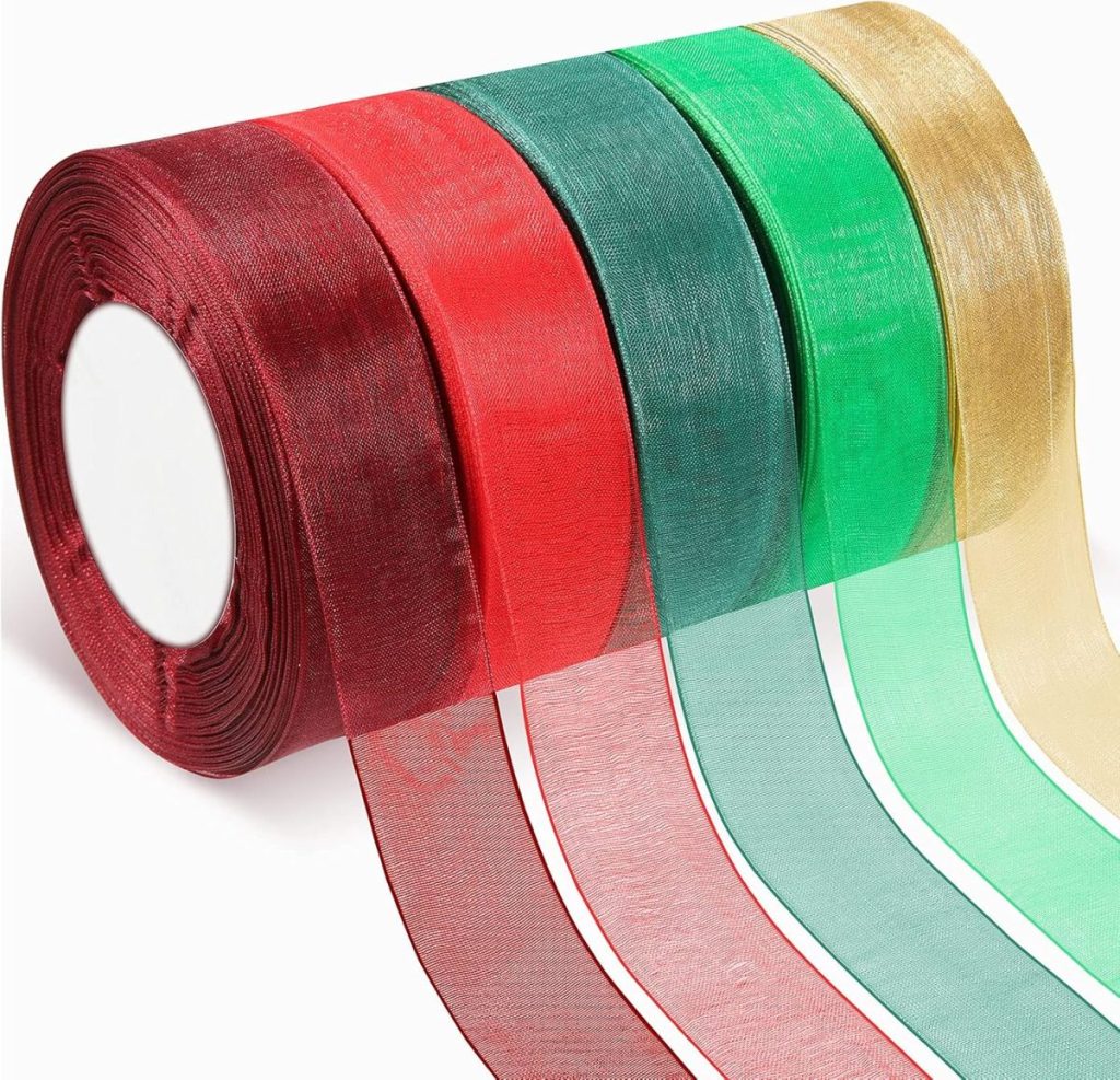 Five rolls of sheer ribbon in maroon, red, green, teal, and gold are elegantly arranged in a row, perfect for adding a touch of flair to gift wrapping.