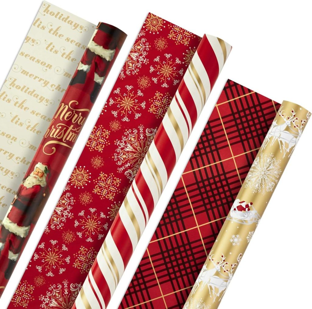 Five rolls of festive gift wrapping paper with Christmas-themed designs, including Santa, text, snowflakes, stripes, plaid, and sleighs.