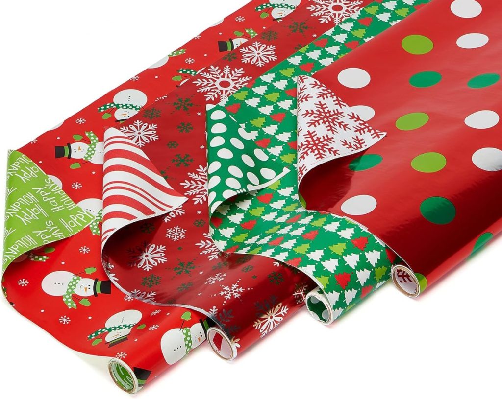 Rolls of festive gift wrapping paper featuring various holiday designs, including snowmen, snowflakes, stripes, polka dots, and Christmas trees, displayed on a flat surface.