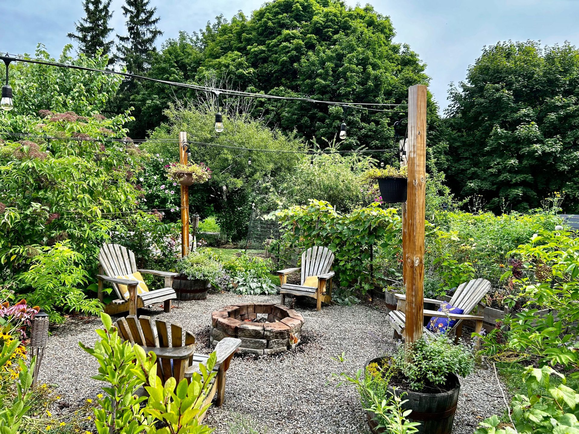 A homemade fire pit surrounded by a lush green garden.