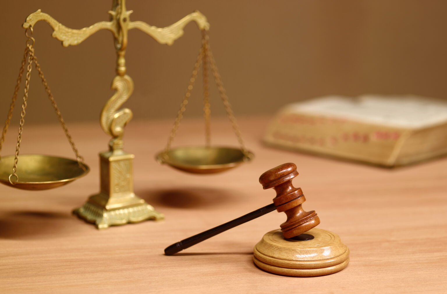 A stock photo of a judge's gavel on a desk, a law book and the scales of justice.