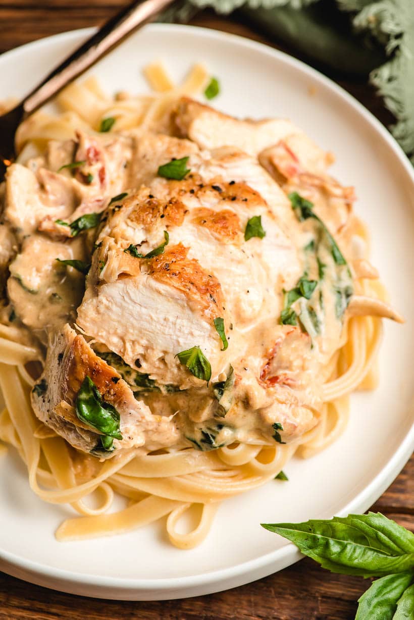 Sliced sauteed chciken on a bed of creamy sun dried tomato pasta.