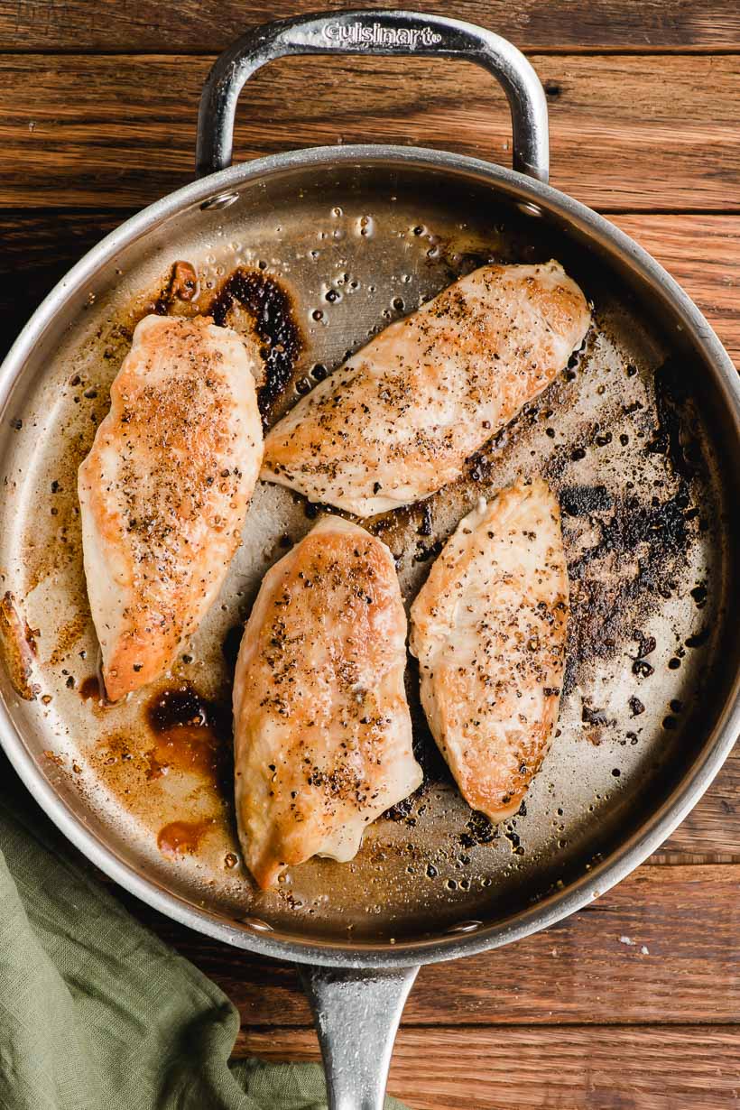 Seared chicken breasts shown in a deep skillet.