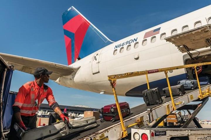 A Delta employee loads baggage onto a plane.