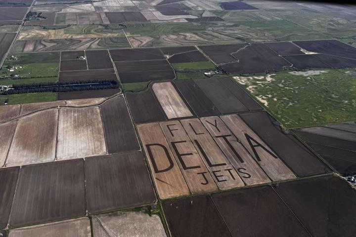 An aerial view of "Fly Delta Jets" carved into the field of a rice farm