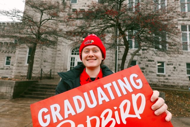 Student holding a Graduating Redbird sign