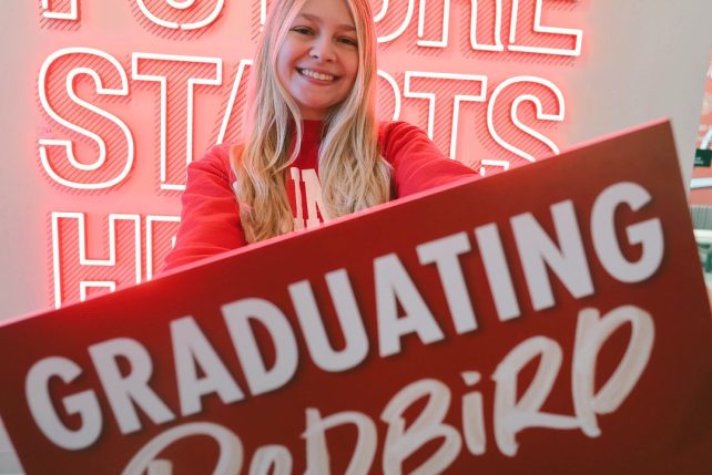 Student holding a Graduating Redbird sign