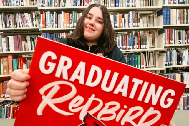 Student holding a Graduating Redbird sign