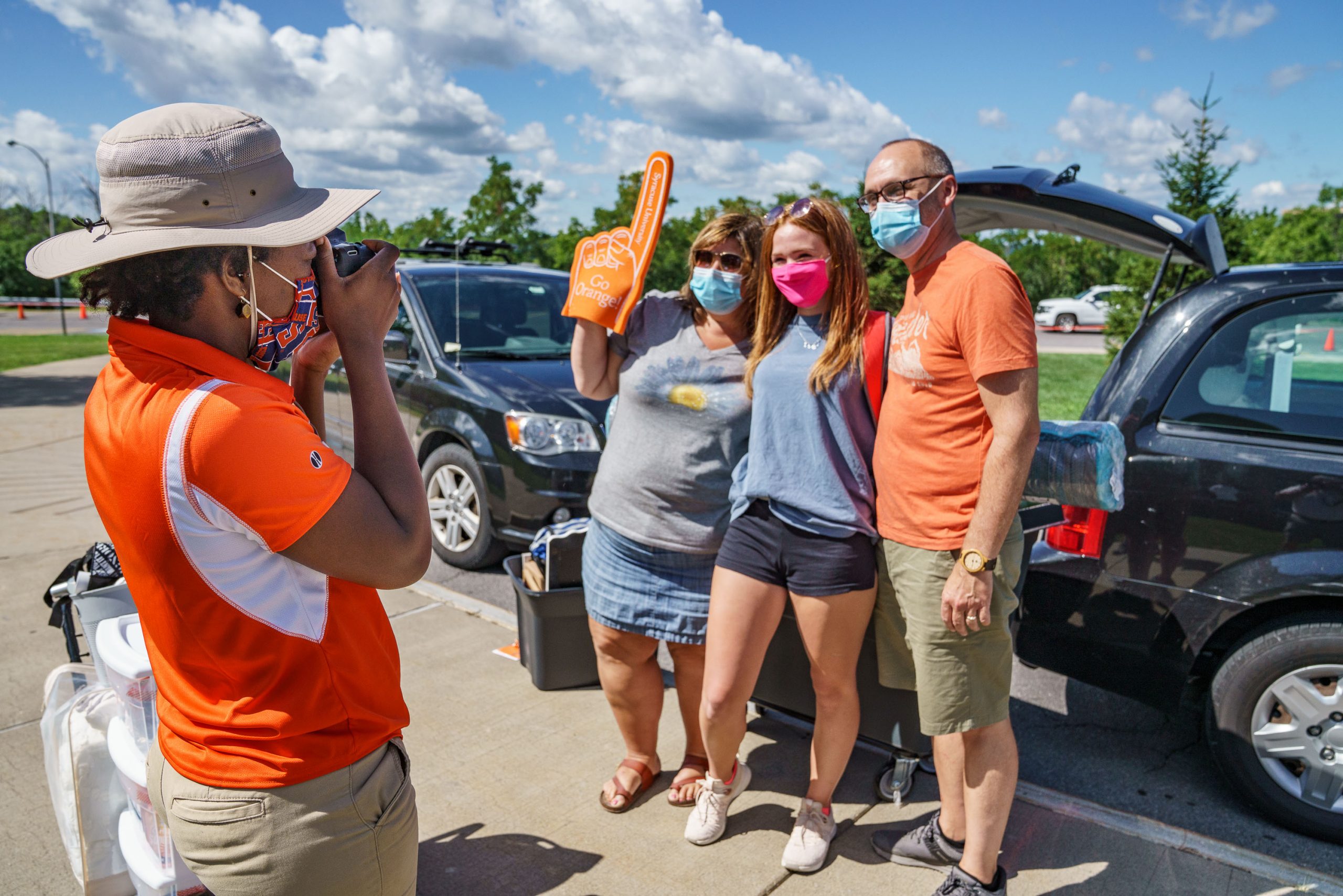 person taking photo of three people standing next to car