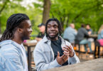 Two African American men have a conversation in a park.