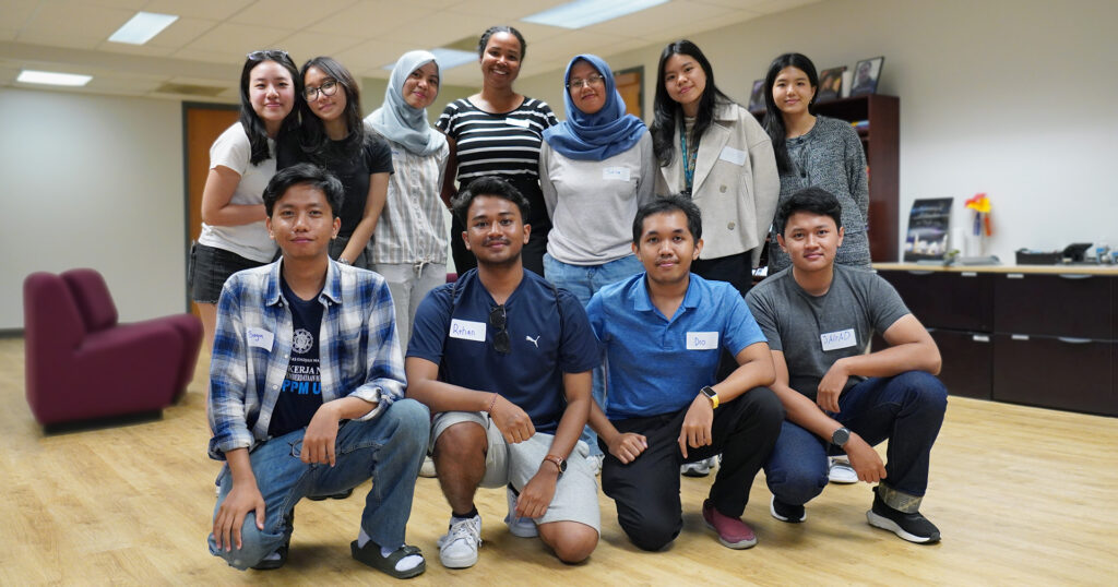 a group of Indonesian students who won an Indonesian International Student Mobility Award scholarship and their program coordinator. Six women stand in the back row and four men are kneeling in the front