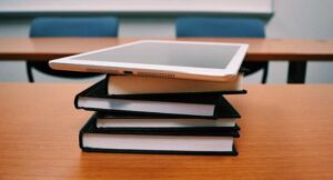 Stack of four books with an ipad on top sitting on a desk