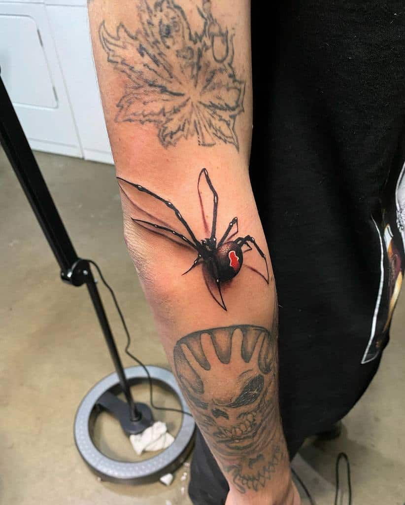 3D tattoo of a black widow spider with a red mark on its back, placed on a forearm