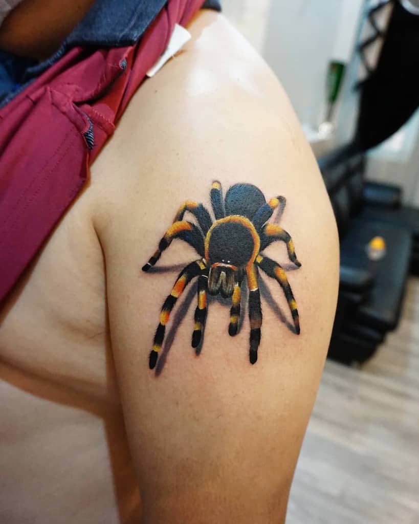 A realistic tarantula tattoo on an upper arm, with detailed color and shading