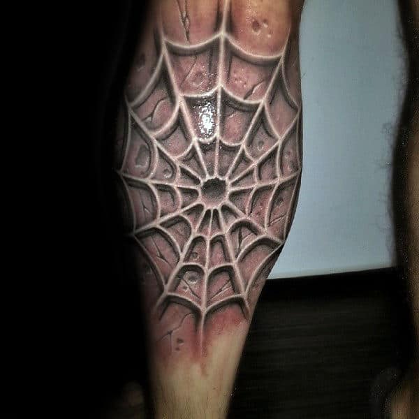 Spider web tattoo on a leg rendered in a detailed, three-dimensional black and white style