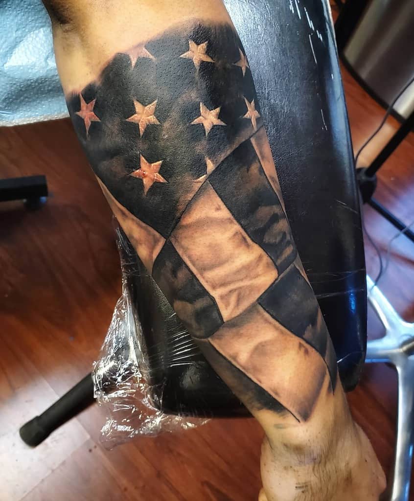 Forearm tattoo of an American flag with realistic details, showing stars and stripes