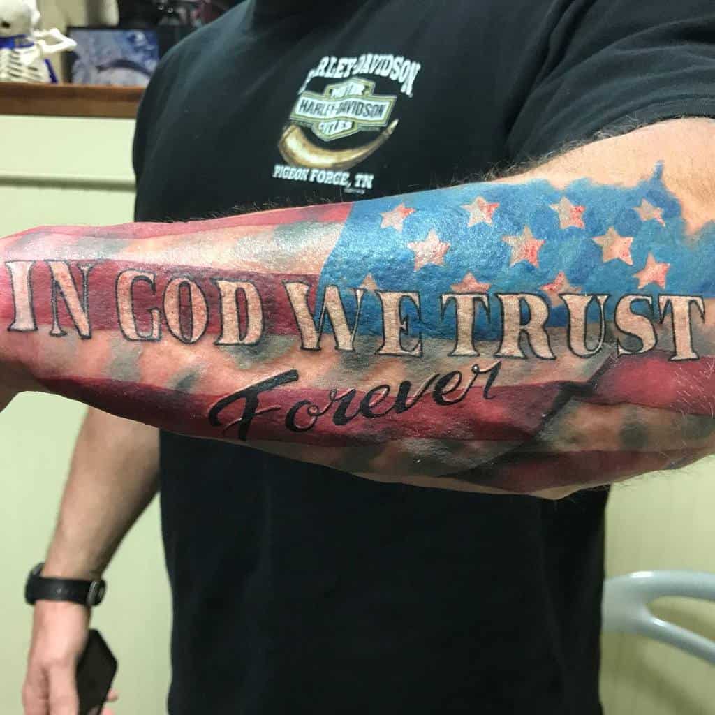 Forearm tattoo with "In God We Trust Forever" over an American flag design