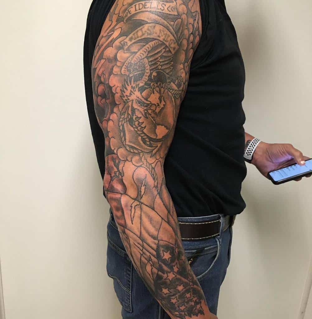 Intricate American flag full-sleeve tattoo, paired with eagle and ‘Semper Fidelis’ banner, showcasing honor and patriotism in fine detail