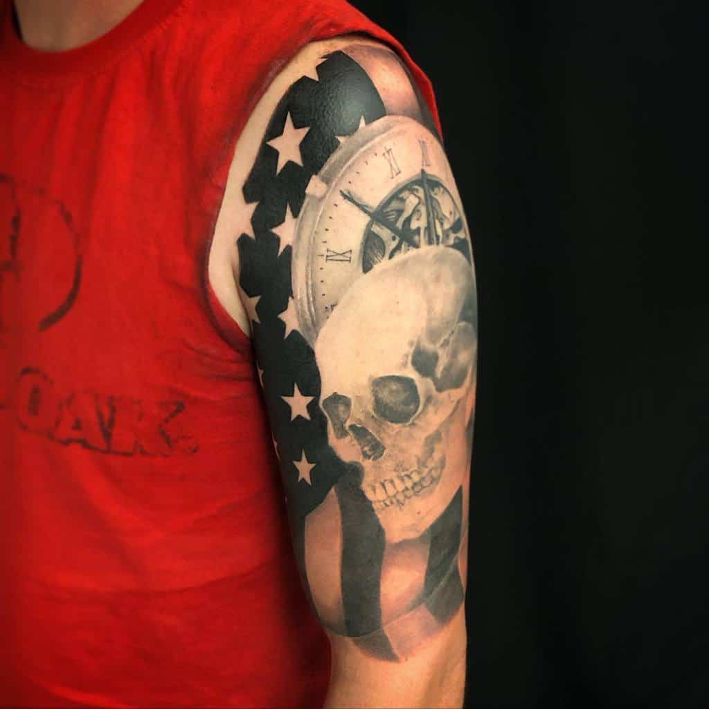 Bold upper-arm tattoo featuring the American flag, a detailed skull, and a vintage clock, symbolizing patriotism and the passage of time