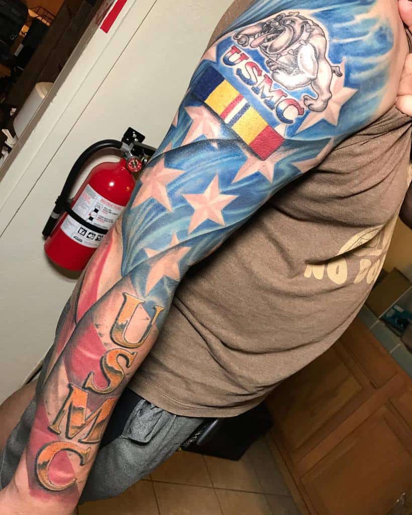 Vivid full-sleeve tattoo showcasing the American flag, USMC logo, and vibrant patriotic symbols to honor military pride and service