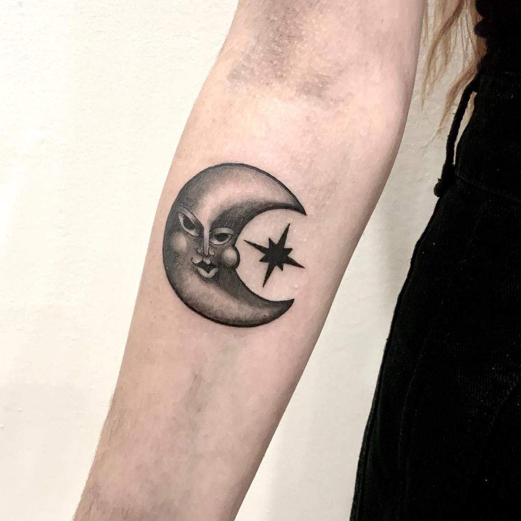 Crescent moon with face and scattered stars on forearm