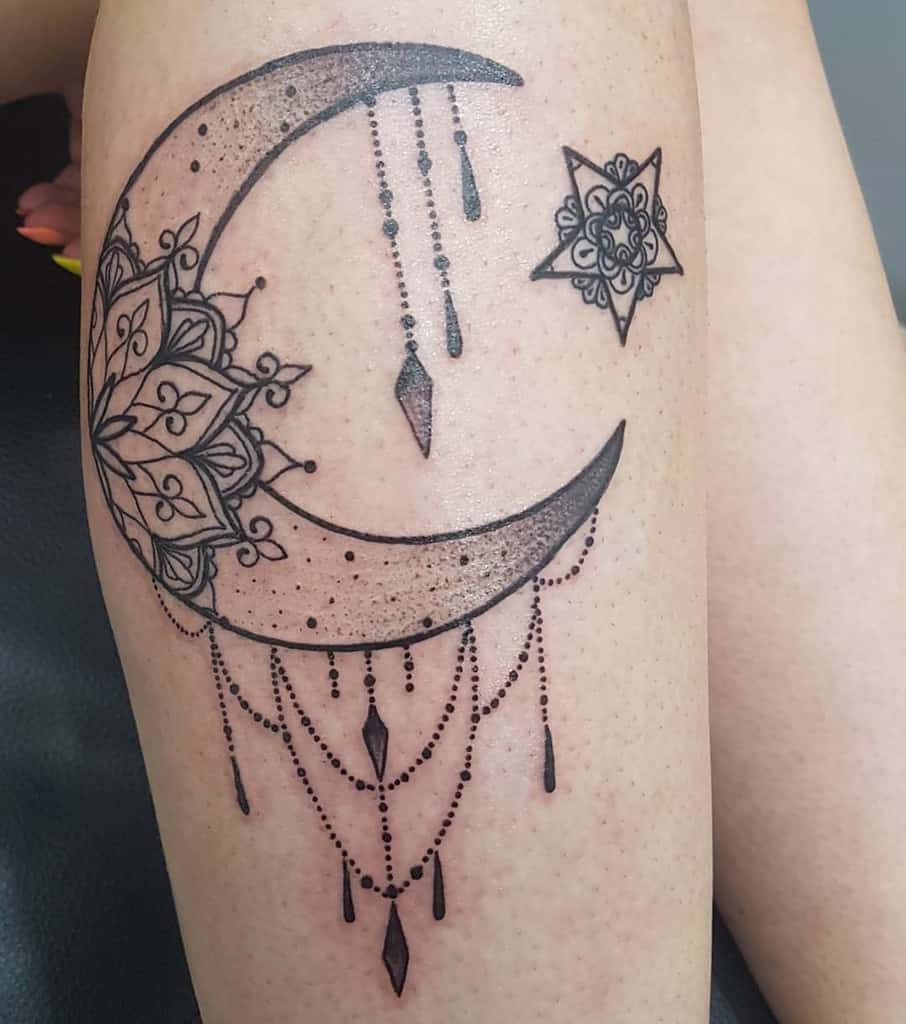 Detailed crescent moon with hanging beads and stars on a person's thigh