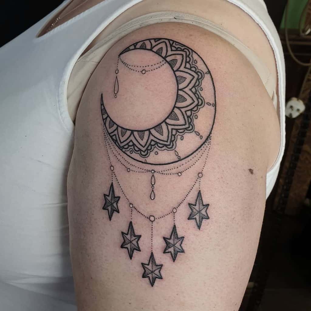 Moon and stars tattoo with intricate mandala details gracefully adorns the upper arm