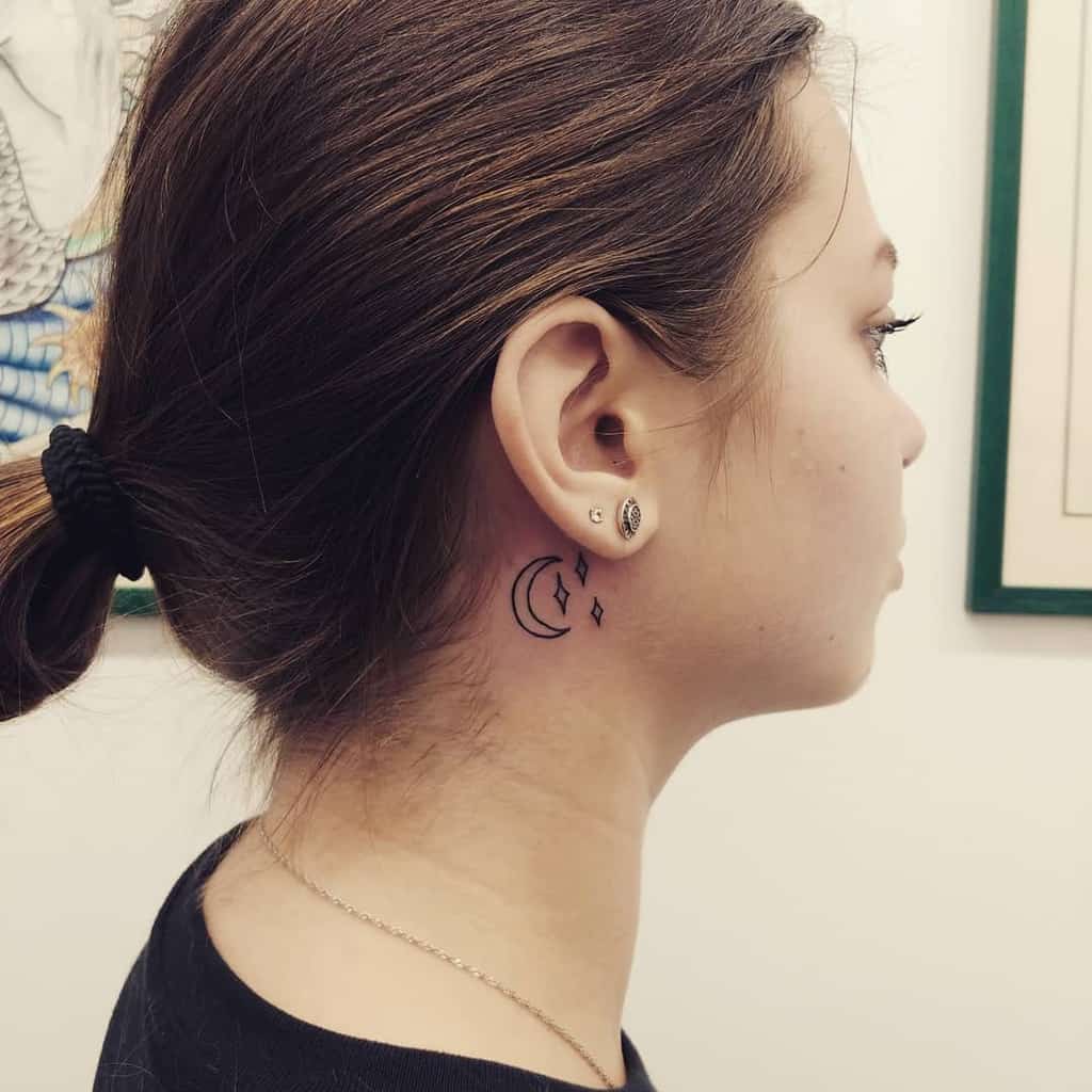 Tattoo of a crescent moon and stars behind an ear