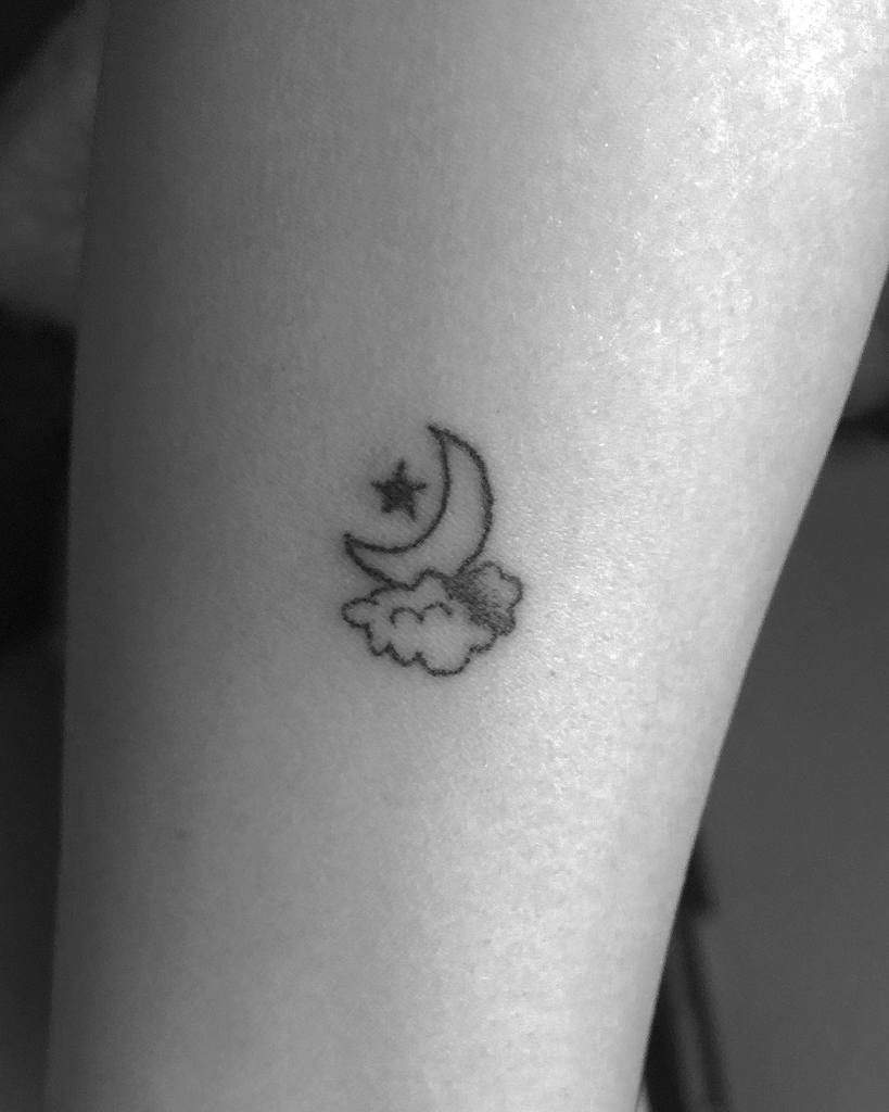 Small tattoo of a crescent moon, tiny stars, and a delicate cloud on a person's skin