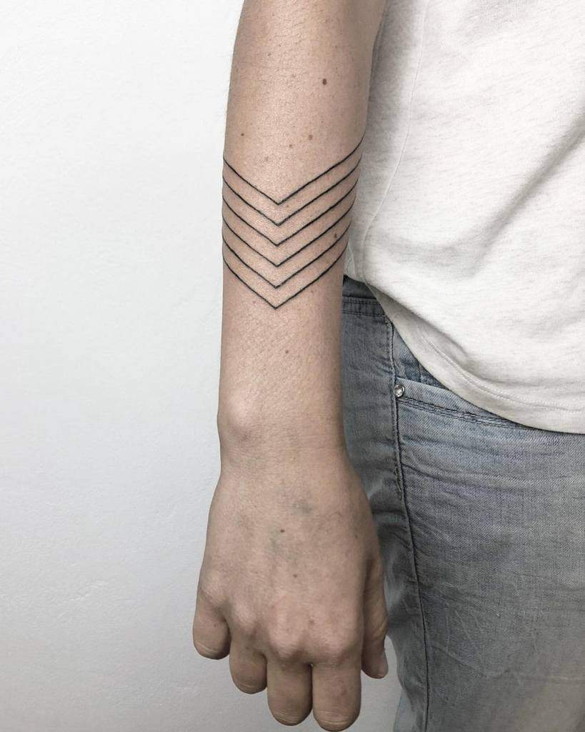 Arm with six chevron line tattoos on the forearm