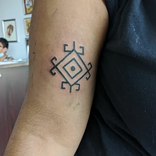 Geometric tattoo with a diamond shape and curved patterns on an arm