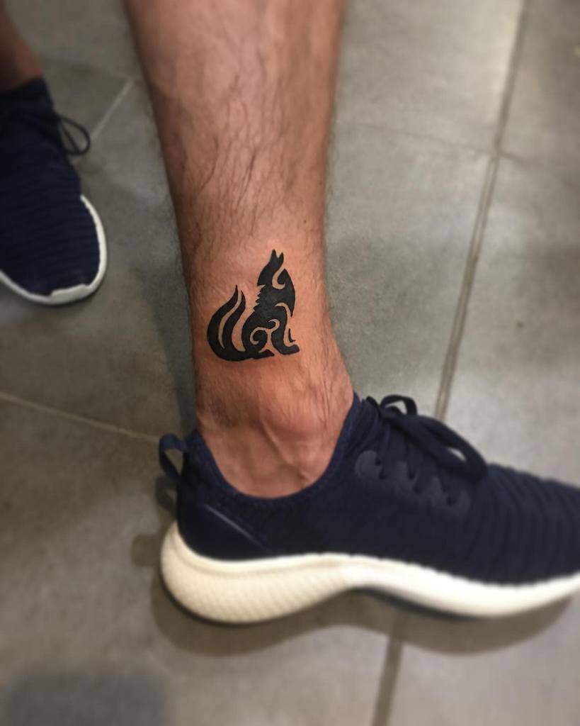 Small tattoo of a stylized, tribal fox on the person's ankle