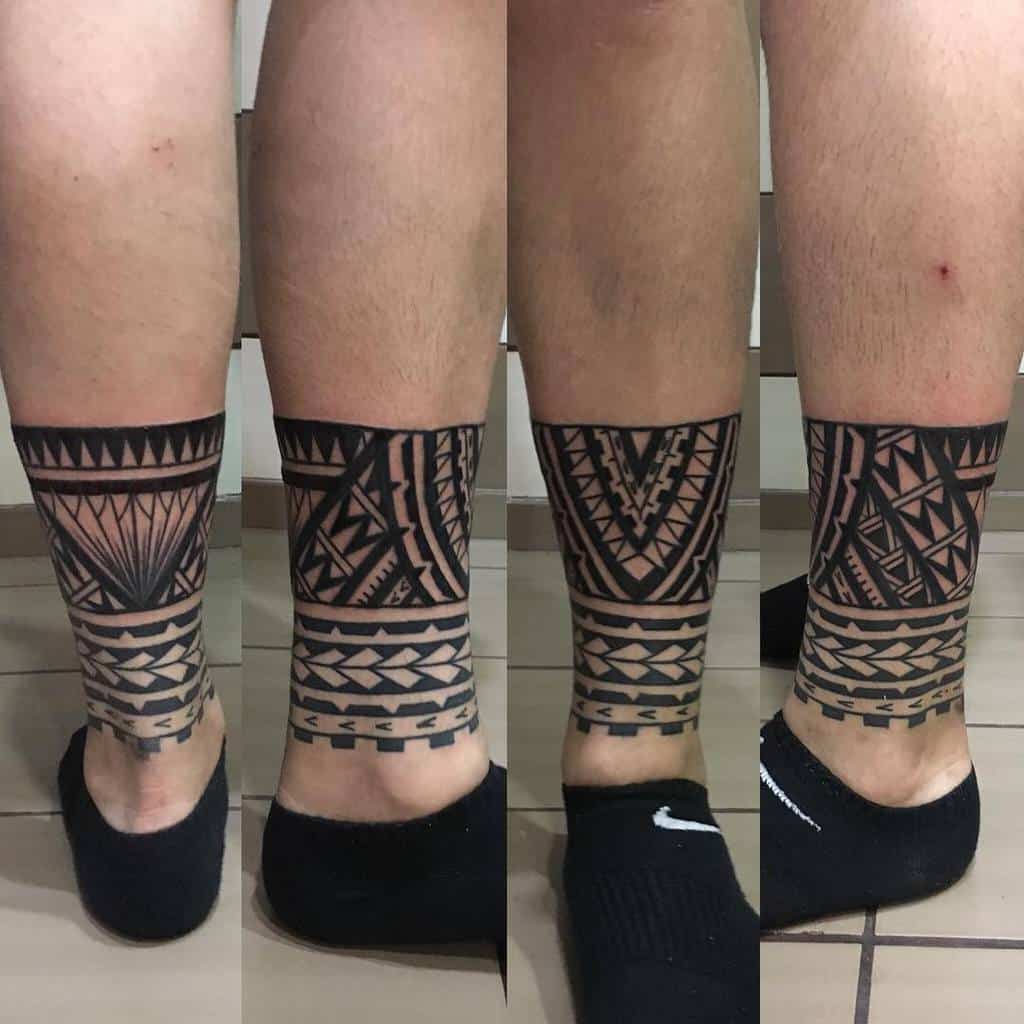 The tattoo features a bold and intricate tribal design wrapping around the ankle, showcasing geometric patterns and sharp line