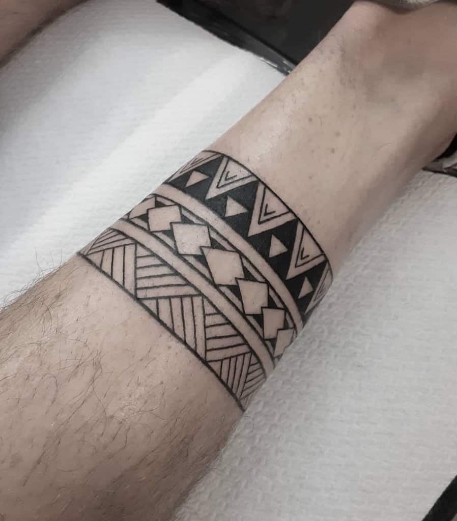 Geometric tribal band tattoo with triangles and diamond shapes adorning a leg