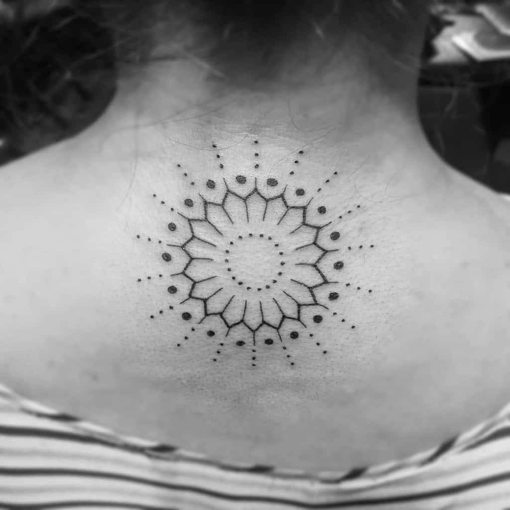 A tribal geometric sunburst tattoo graces the back of a neck