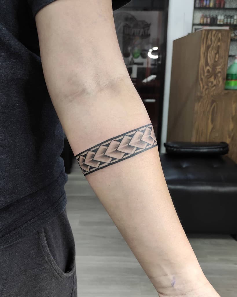 Arm with a tribal geometric arrow-band tattoo in black and brown