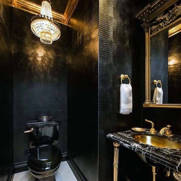 Luxurious black bathroom with gold accents, marble sink, and crystal chandelier.