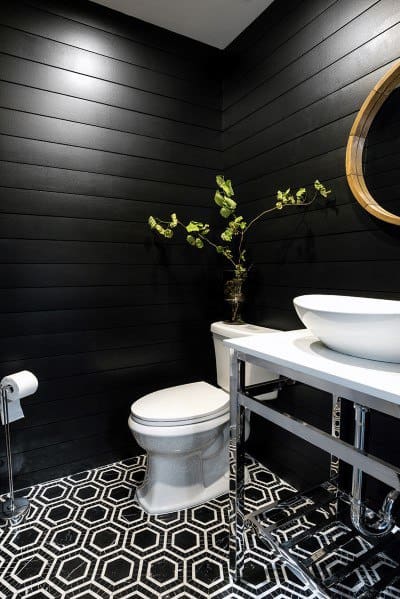 Black bathroom with hexagonal patterned floor tiles and white sink.