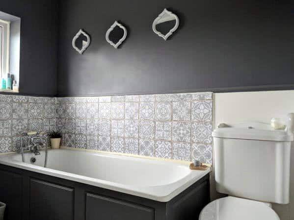 White bathroom with patterned tile, black cabinets, and bathtub.