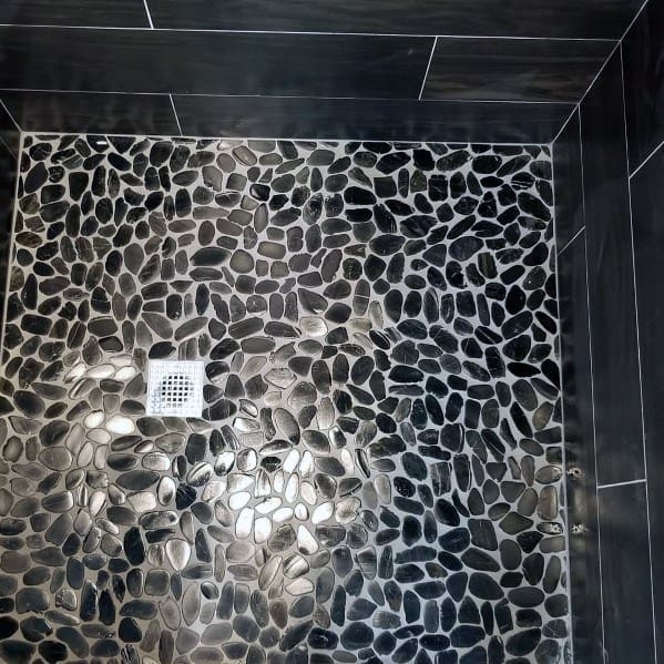 Black pebble stone shower floor tiles with dark wall accents.