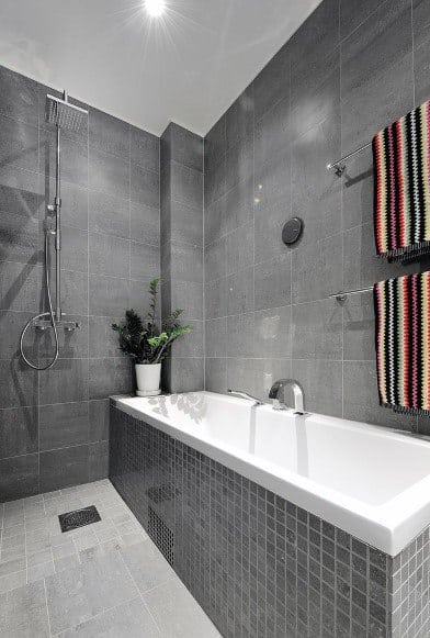 Contemporary bathroom with grey tiles, built-in bathtub, and rainfall shower.