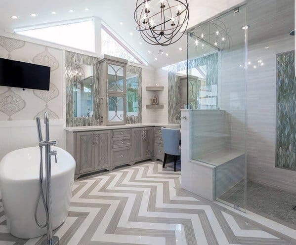 Modern bathroom with glass shower, built-in seat, freestanding tub, and chevron floor pattern.