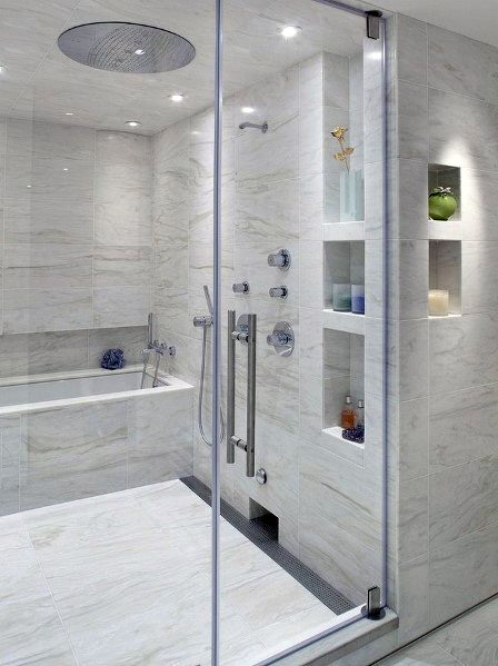 Bathroom with marble tiles, built-in shower niches, and a large glass-enclosed shower and tub combo.