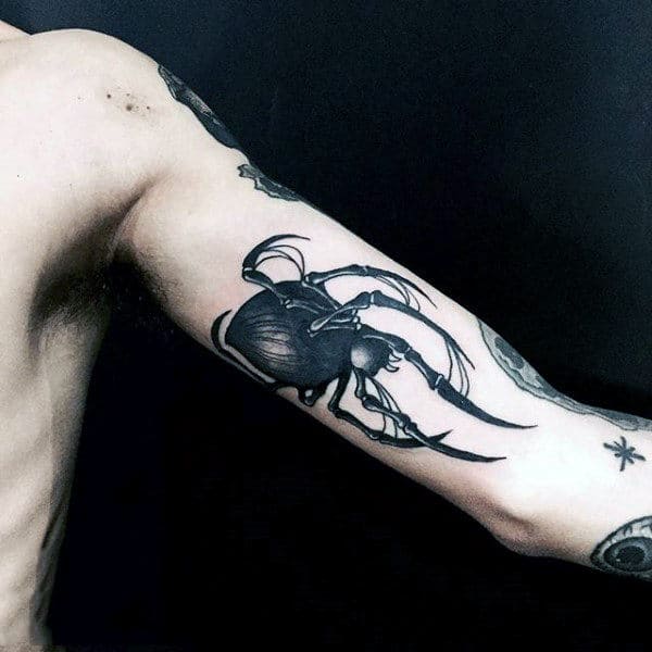 Black beetle tattoo with long antennae on inner upper arm