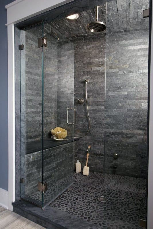 Modern grey shower with pebble stone floor, glass enclosure, and built-in bench.