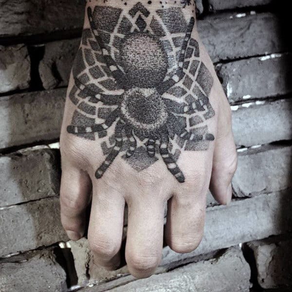 Hand with a detailed black ink spider tattoo on the back