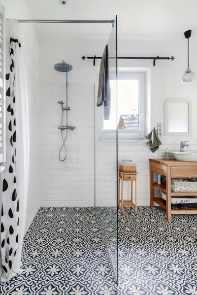 Contemporary shower with black and white patterned floor tiles and glass partition.